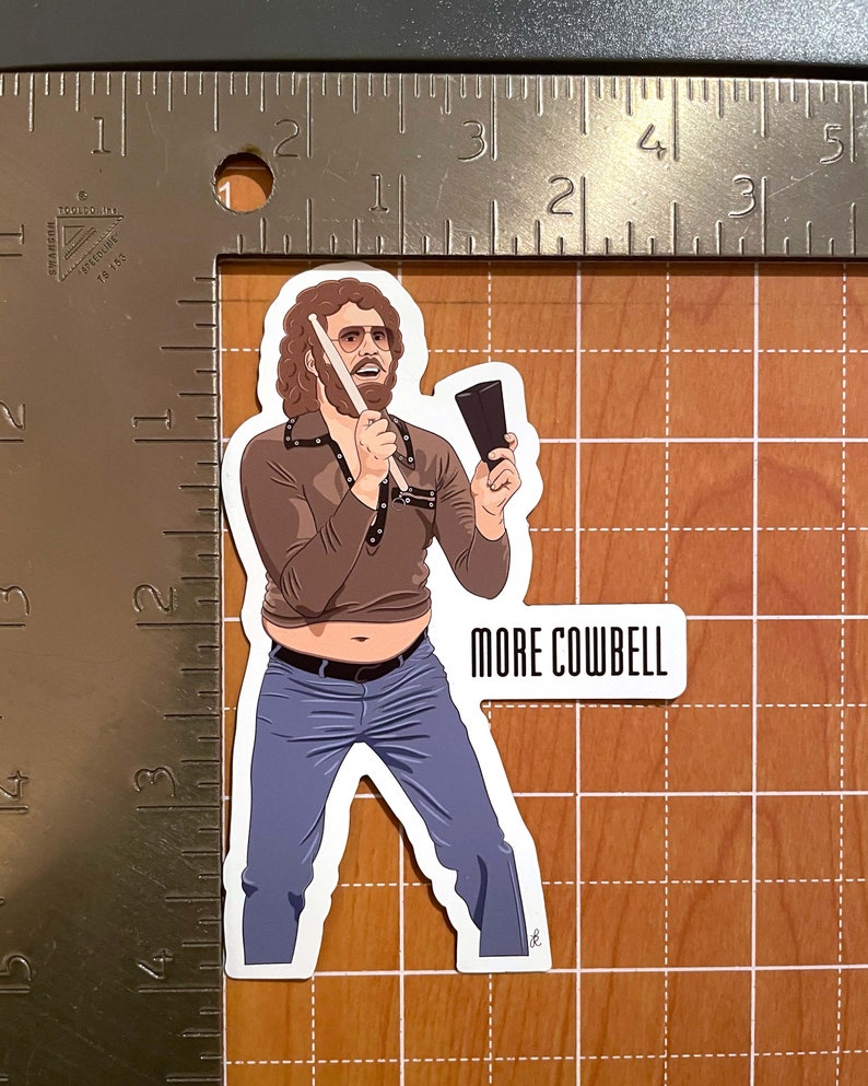 May include: A cartoon illustration of a man with curly brown hair and a mustache playing a cowbell with a drumstick. He is wearing a brown shirt with a black belt, blue jeans, and a pair of glasses. The text "MORE COWBELL" is written below the image.