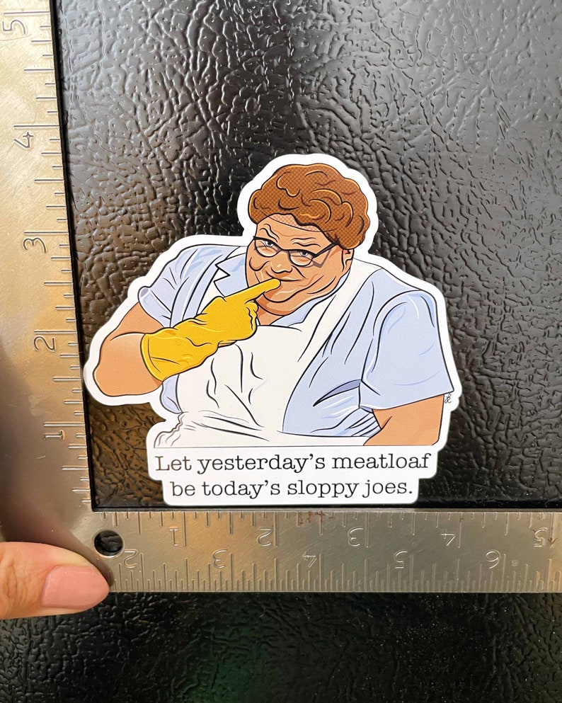 May include: A sticker featuring a cartoon illustration of a woman with brown hair and glasses wearing a blue shirt and yellow gloves. The text on the sticker reads "Let yesterday's meatloaf be today's sloppy joes."