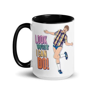 May include: White ceramic mug with a black interior and handle. The mug features a colorful illustration of a person with the text "LOOK WHAT I CAN DO!" printed on the side.