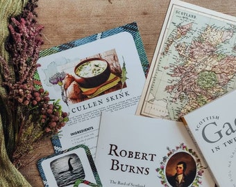 Puede incluir: Un juego de cartas con temas escoceses, que incluye un mapa de Escocia, un retrato de Robert Burns e ilustraciones de un cardo, un kilt y una bebida tradicional escocesa. Las cartas están sobre una superficie de madera con una bufanda verde y un libro sobre gaélico escocés.