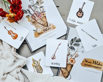 May include: A set of printable flashcards featuring illustrations of various musical instruments, including a cello, f-style mandolin, flute, and akonting. The cards are part of a student workbook titled "Woven Melodies" by Thistles and Biscuits.