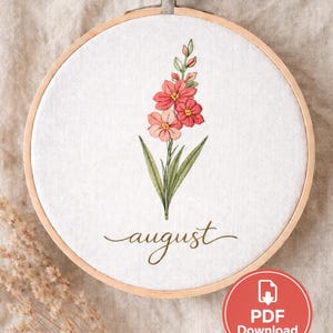 May include: Embroidered floral hoop art featuring a pink and red flower design with green leaves. The word "august" is written in cursive below the flowers. The embroidery is set in a wooden hoop.
