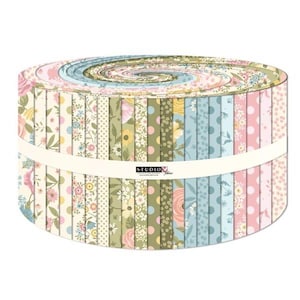May include: A fabric jelly roll featuring a collection of tightly wound strips with various floral, polka dot, and botanical patterns in shades of pink, blue, yellow, and green. A white paper band with the text S.T.U.D.I.O. wraps around the center.