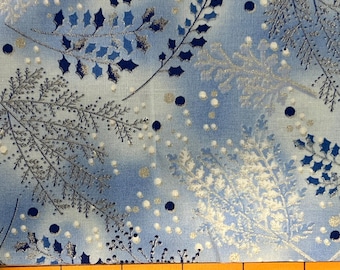 May include: A light blue fabric with a winter-themed pattern. The design features silver and dark blue branches, along with white and dark blue dots. The fabric is measured with an orange ruler.