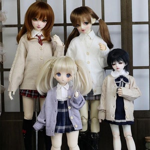 May include: Four dolls wearing different coloured cardigans and skirts. The dolls are all wearing white shirts and have long hair. The dolls are standing in front of a wooden background.