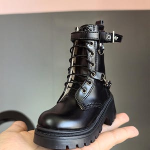 May include: Black leather ankle boots with a chunky platform sole and lace-up front. The boots have a buckle strap at the ankle and a silver chain detail.