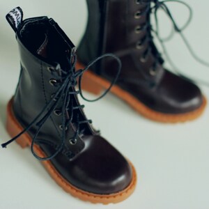 May include: A pair of dark brown leather boots with laces and a zipper. The boots have a round toe and a light brown sole. The boots are designed with a classic style.