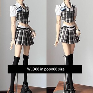 May include: A doll wearing a school uniform consisting of a white collared shirt, plaid vest and skirt, black knee-high socks, and platform shoes. The doll has elf-like ears and is wearing a black hat. The text "WLD68 in popo68 size" is displayed.