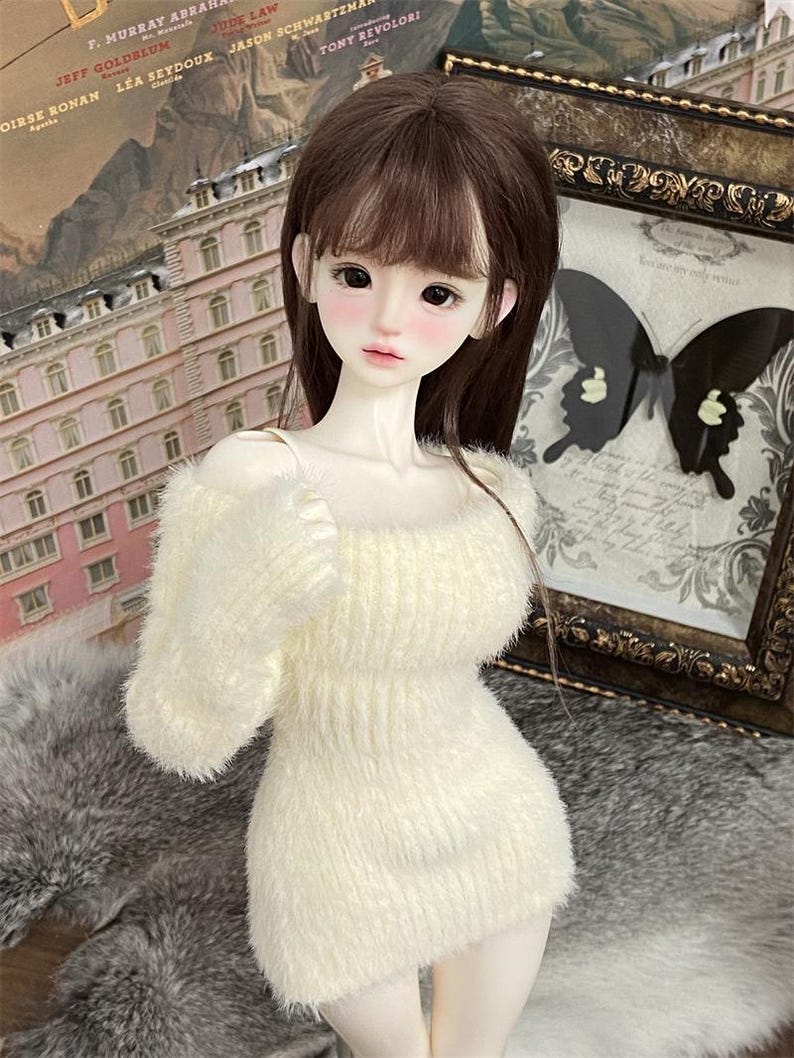 Puede incluir: Un vestido de su&eacute;ter blanco y peludo con cuello redondo y mangas largas. El vestido est&aacute; hecho de un material suave y esponjoso y tiene una silueta ligeramente ajustada.
