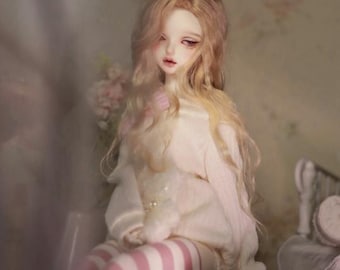May include: A doll with long blonde hair wearing a white sweater and pink and white striped stockings. The doll is sitting on a pink and white ornate stool.