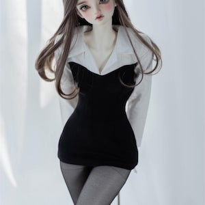 May include: A doll with long brown hair wearing a black dress and a white collared shirt. The doll is posed with one leg raised and is wearing black heels.