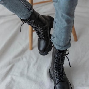 May include: Black leather lace-up boots with a chunky sole. The boots are worn with blue jeans.