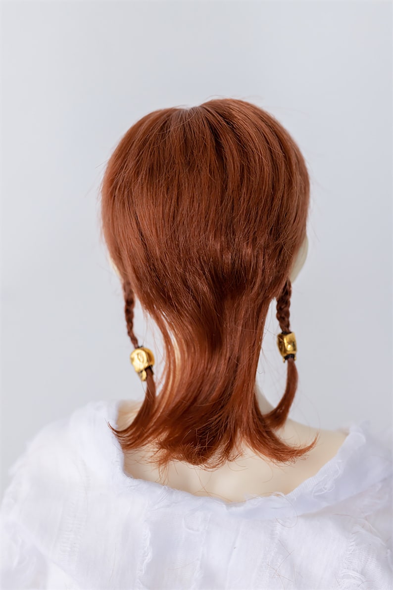 May include: A long, straight, auburn-colored wig with two braids tied with gold beads.