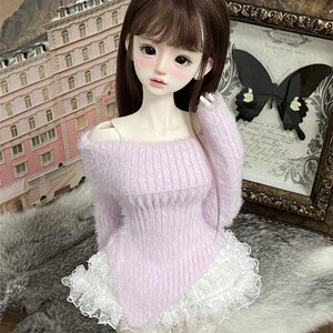 Puede incluir: Una mu&ntilde;eca con un su&eacute;ter de color morado claro y peludo con un borde de encaje blanco. La mu&ntilde;eca tiene el pelo largo y casta&ntilde;o y lleva una falda blanca.