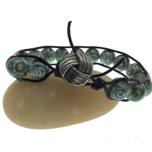 May include: A black leather bracelet with green and white agate beads and a silver knot clasp.