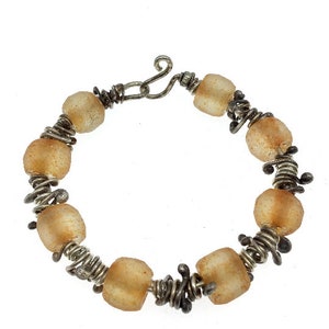 May include: A silver and amber beaded bracelet with a clasp fastening. The beads are irregularly shaped and have a translucent, slightly cloudy appearance.