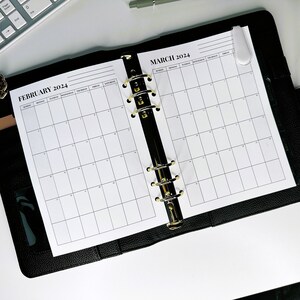 May include: A black leather bound planner with gold rings. The planner has two open pages with monthly calendars for February and March 2024.