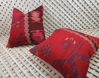 May include: Two red throw pillows with geometric patterns. The pillows are made of a woven fabric and have a soft, textured feel.