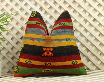 May include: Multicolored striped throw pillow with geometric patterns in shades of red, yellow, green, blue, and black. The pillow is made of woven fabric and has a fringed edge.