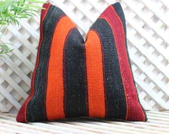 May include: A striped throw pillow with black, orange, and red stripes. The pillow is made of a woven fabric and has a soft, textured feel.