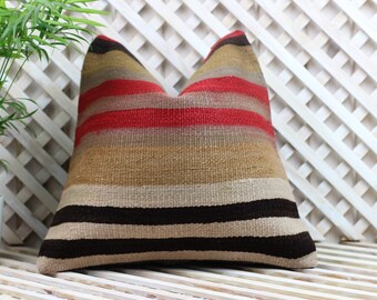 May include: Striped throw pillow with a brown, beige, and red color scheme. The pillow is made of a woven fabric and has a rectangular shape.