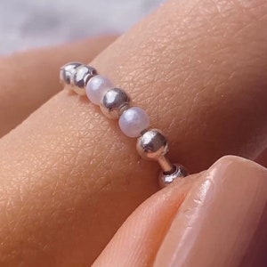 Puede incluir: Un anillo de plata con cuentas de plata y blancas alternas.