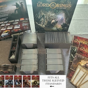 May include: A set of gray card storage boxes for the Lord of the Rings card game. The boxes are filled with sleeved cards. The image also shows the game box, rule books, and individual cards.