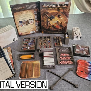 May include: A brown and grey board game organiser with multiple compartments for storing game pieces, cards, and dice. The organiser is designed for the board game Gloomhaven: Jaws of the Lion. The organiser is shown on a grey surface with a rulebook and other game components.