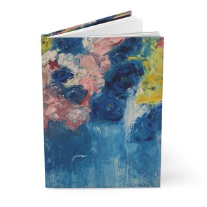 Może przedstawiać: Dziennik z kolorowym, abstrakcyjnym wzorem kwiatowym na okładce. Kwiaty są namalowane w odcieniach niebieskiego, różowego, białego i żółtego. Tło jest ciemnoniebieskie.