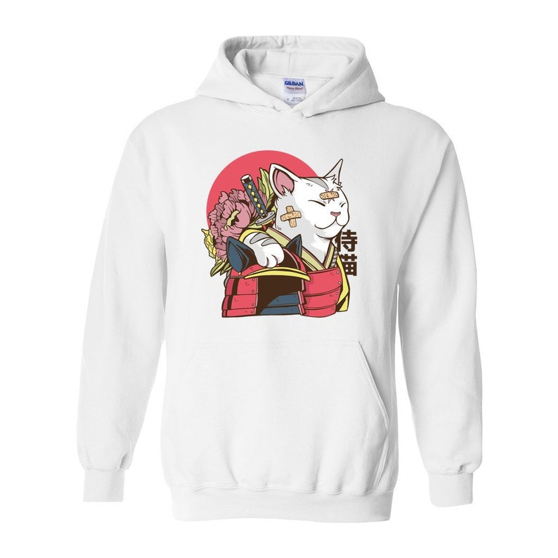 Peut inclure: Sweat-shirt &agrave; capuche blanc avec un motif repr&eacute;sentant un chat blanc portant une armure de samoura&iuml; rouge et or, tenant une &eacute;p&eacute;e et une fleur rose. Le chat a un bandage sur l'&oelig;il et le texte "戦猫" est imprim&eacute; sur le c&ocirc;t&eacute; droit de l'image.