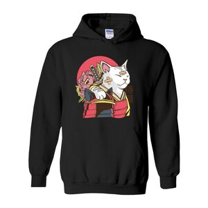 Peut inclure: Sweat-shirt &agrave; capuche noir avec un chat blanc portant une tenue de samoura&iuml; rouge et noire et tenant une &eacute;p&eacute;e. Le chat a des bandages sur le visage et une fleur rose derri&egrave;re lui. Le texte "侍猫" est imprim&eacute; sur le sweat-shirt.