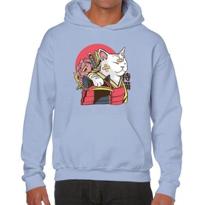 Peut inclure: Un sweat-shirt bleu clair avec un motif repr&eacute;sentant un chat blanc portant une armure de samoura&iuml; et tenant un katana. Le chat a des bandages sur le visage et est entour&eacute; d'un cercle rouge et de fleurs roses. Le mot japonais "侍猫" est imprim&eacute; sur le sweat-shirt.