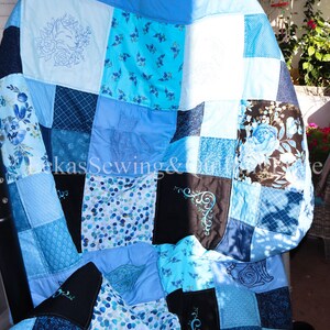 Könnte beinhalten: Eine Patchwork-Decke mit verschiedenen Blautönen, darunter hellblaue, marineblaue und türkisfarbene Quadrate. Die Decke zeigt gestickte Blumen- und Katzenmotive sowie gemusterte Stoffquadrate mit Blumen und Punkten. Der Text lautet LukasSewing&Crafts.