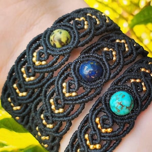 Puede incluir: Tres pulseras de macramé negras con detalles dorados y piedras preciosas en el centro. Cada pulsera presenta una piedra preciosa diferente: verde, azul y turquesa. Las pulseras están hechas a mano con un diseño tejido detallado.