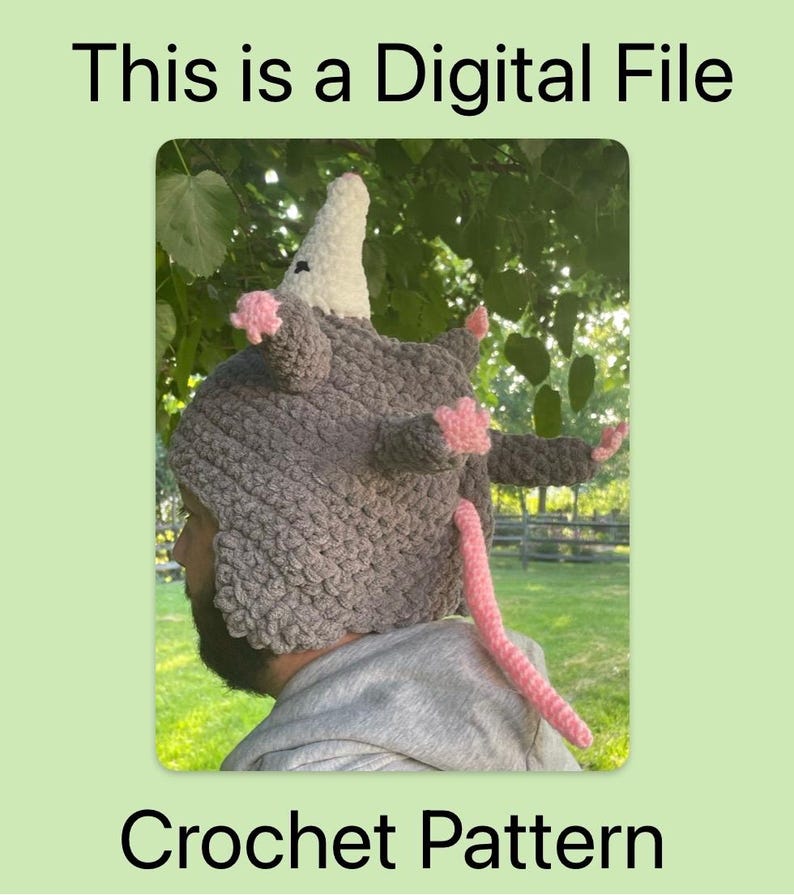 May include: A grey crochet possum hat with a white nose, pink ears, and a pink tail. The text "This is a Digital File" and "Crochet Pattern" are displayed on a green background.