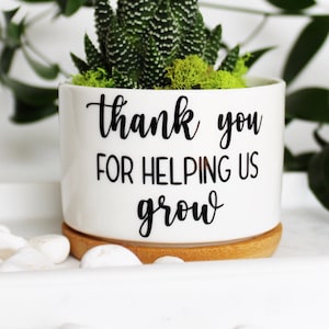 May include: White ceramic planter with a succulent plant and the text "thank you for helping us grow".