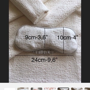 May include: A light gray eye mask with a white trim. The eye mask is 9 cm - 3.6 inches wide, 10 cm - 4 inches long, and 24 cm - 9.6 inches in circumference.