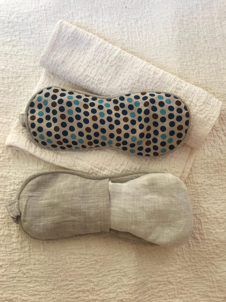 May include: Two eye masks, one with a blue and brown polka dot pattern and one plain light gray.