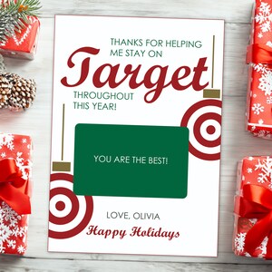 May include: A white card with red and gold accents featuring a red target graphic and the text "Thanks for helping me stay on Target throughout this year! You are the best! Love, Olivia Happy Holidays".