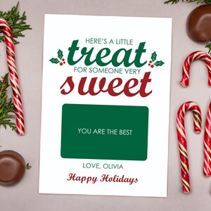 May include: A white card with green and red text that reads "Here's a little treat for someone very sweet". The card has a green rectangle with the text "You are the best" and the text "Love, Olivia" and "Happy Holidays" in red. The card is surrounded by candy canes and chocolate candies.