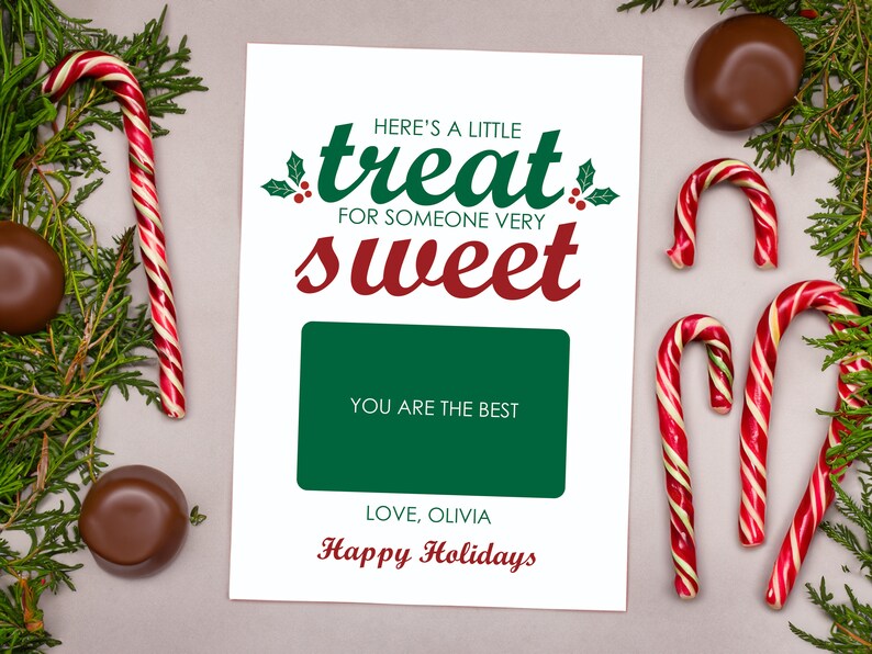 May include: A white card with green and red text that reads "Here's a little treat for someone very sweet". The card has a green rectangle with the text "You are the best" and the text "Love, Olivia" and "Happy Holidays" in red. The card is surrounded by candy canes and chocolate candies.