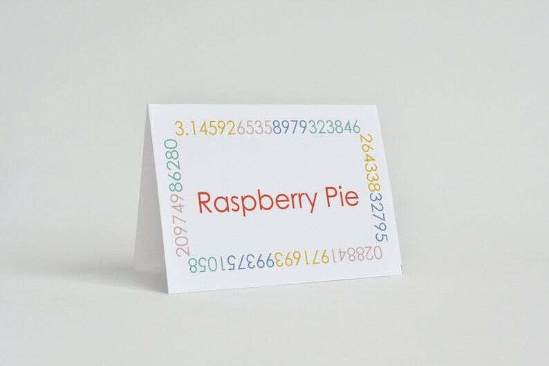 K&ouml;nnte beinhalten: Eine wei&szlig;e Karte mit dem Text "Raspberry Pie" in Rot. Die Karte ist von einem Rand aus bunten Zahlen umgeben.