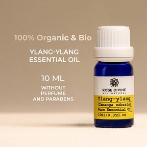 Puede incluir: Una botella de 10 ml de aceite esencial de Ylang-Ylang 100% orgánico y bio. La botella es azul con una tapa blanca y una etiqueta que dice "Rose Divine All Natural Ylang-Ylang (Cananga odorata) Pure Essential Oil 10ml/0.35fl.oz".