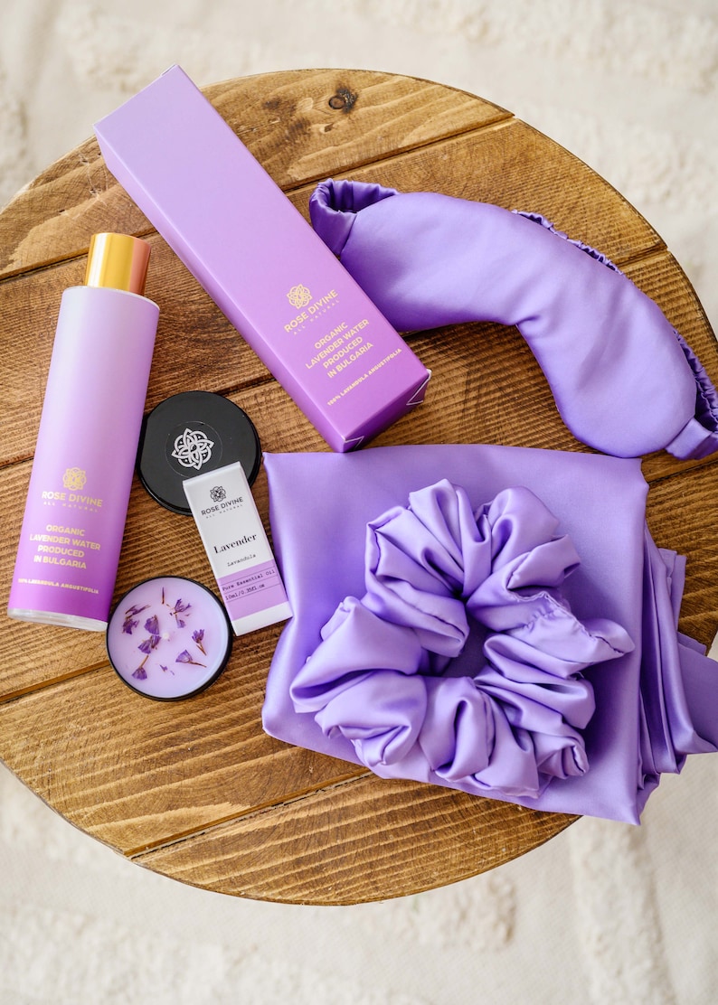 May include: A lavender-themed self-care gift set with a purple satin sleep mask, a satin scrunchie, a bottle of organic lavender water, a small bottle of lavender essential oil, and a lavender candle.