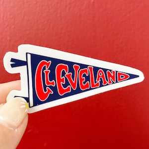 May include: A white pennant with a blue background and red lettering that says "CLEVELAND".