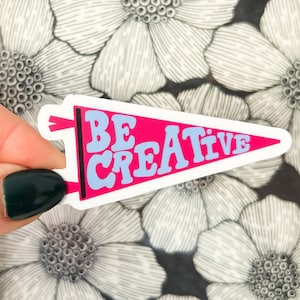 May include: A pink and blue pennant sticker with the text "BE CREATIVE" in white letters.