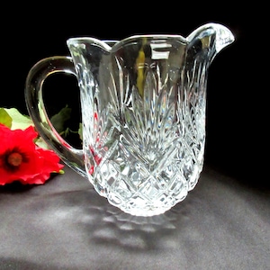 Könnte beinhalten: Eine klare Glaskanne mit einem Diamantenmuster. Die Kanne hat einen Griff und eine breite Öffnung.