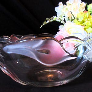 Könnte beinhalten: Eine klare Glasschale mit gewelltem Rand, die ein rosa und weißes Innendesign aufweist. Die Schale ist mit bunten Blumen gefüllt, darunter weiße, gelbe und rosa Blüten. Die Schale wird wahrscheinlich zu dekorativen Zwecken verwendet.