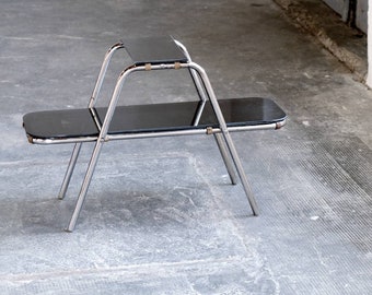 May include: A chrome and black glass nesting table set with two tiers. The table has a simple, modern design with a rectangular top and four legs.