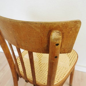 May include: A wooden chair with a curved back and a woven cane seat. The chair is made of light brown wood and has a simple, classic design.